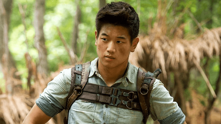 Man with black hair and leather straps across his shoulders, standing outdoors